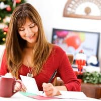 a smiling woman writes a greeting card
