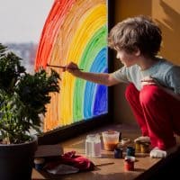 boy painting a rainbow on the window