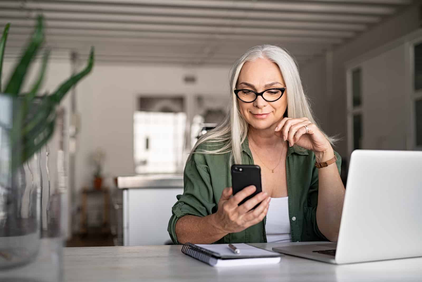 a blonde-haired woman with glasses on her head holds a cell phone in her hand while sitting at a table