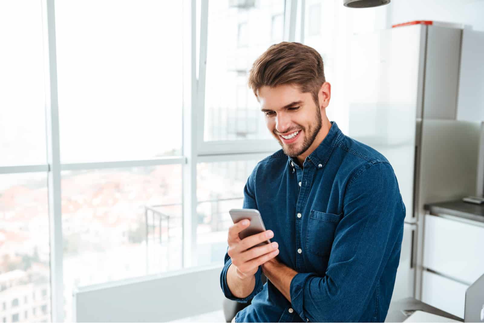 a smiling man leaning on a hundred keys on the phone