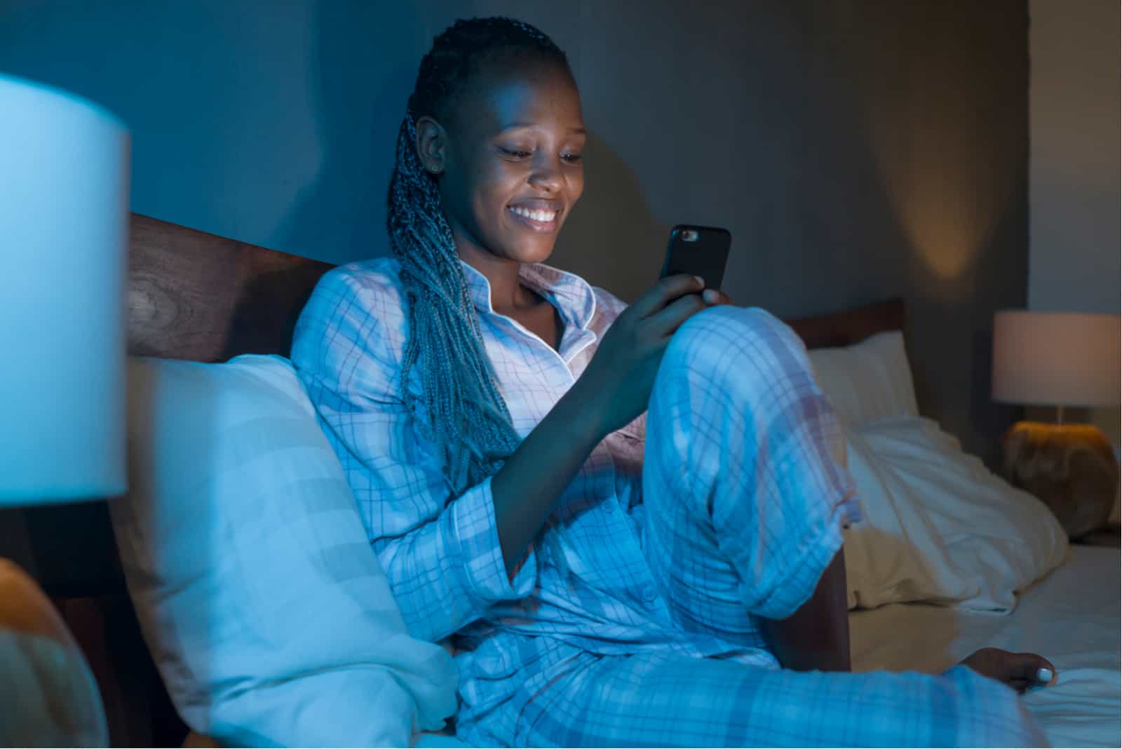 woman sitting on her bed texting