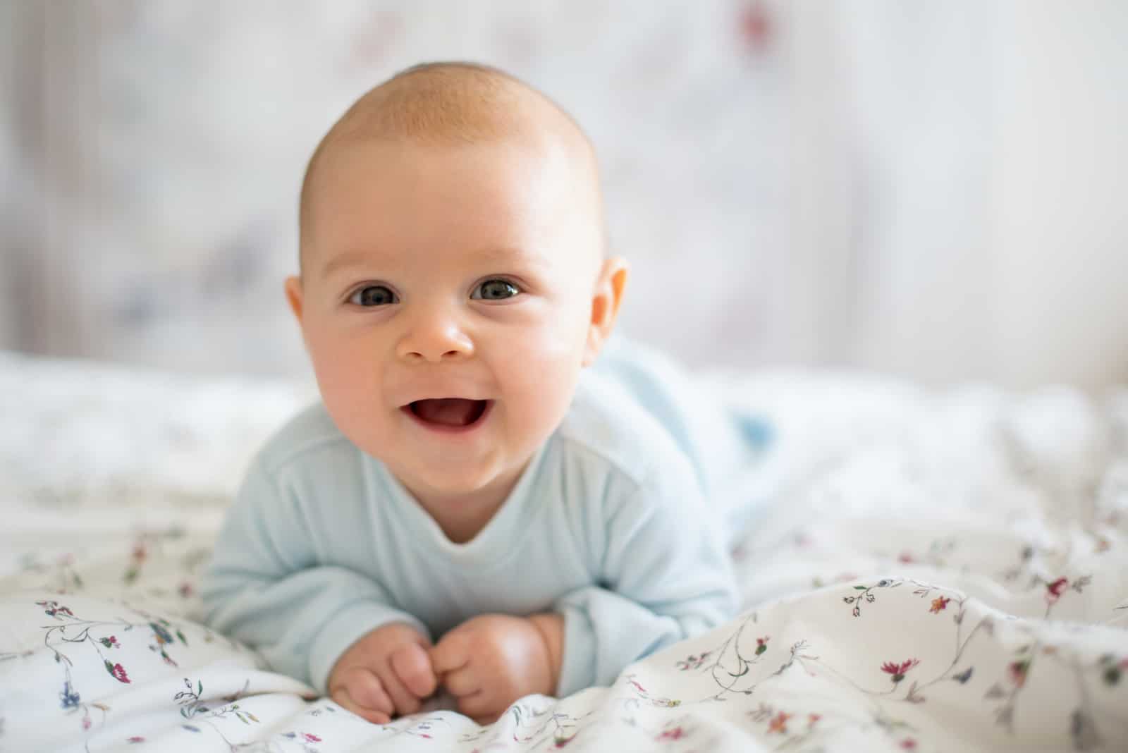 Newborn kid during tummy time smiling happily 