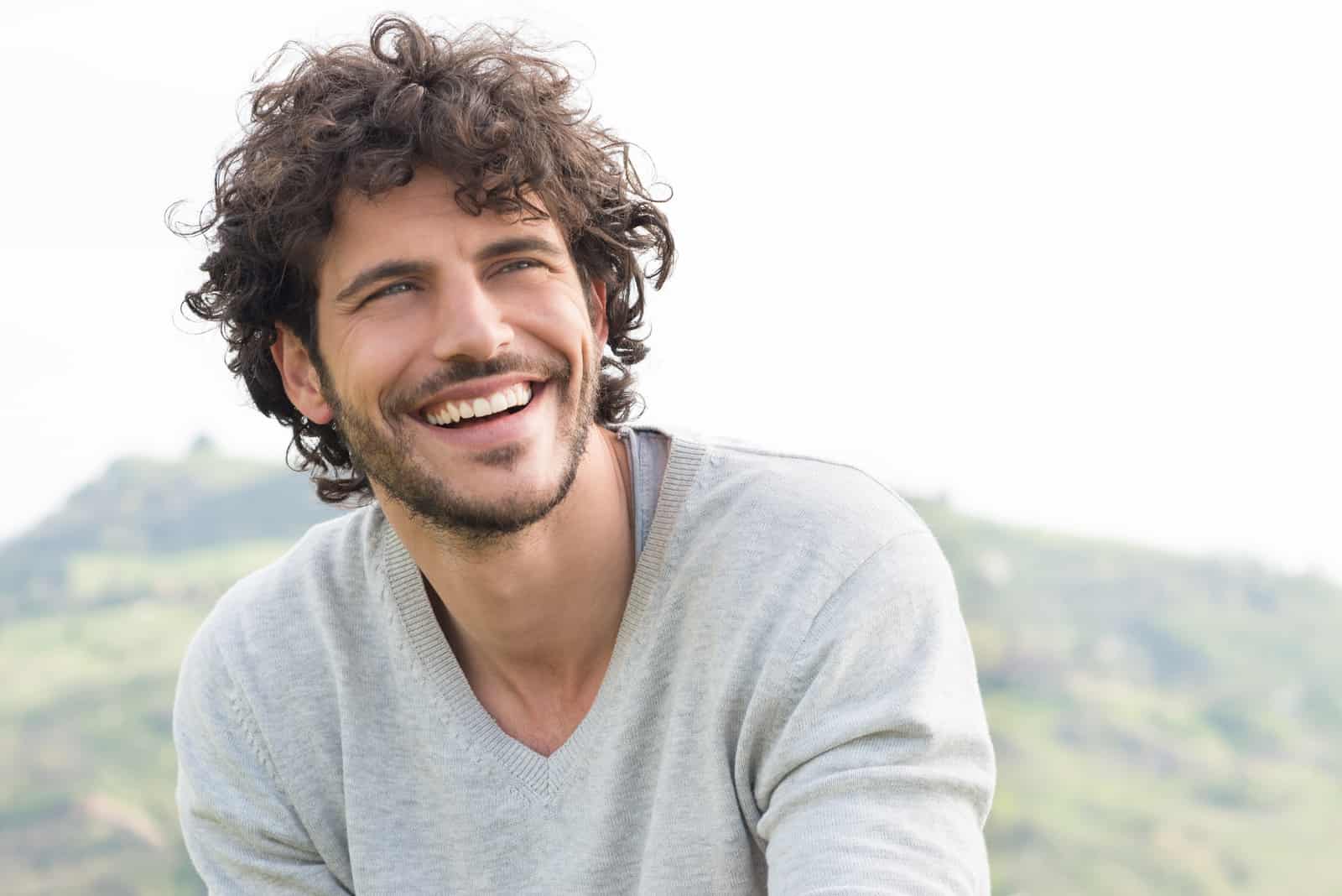 un hombre guapo y sonriente con el pelo encrespado