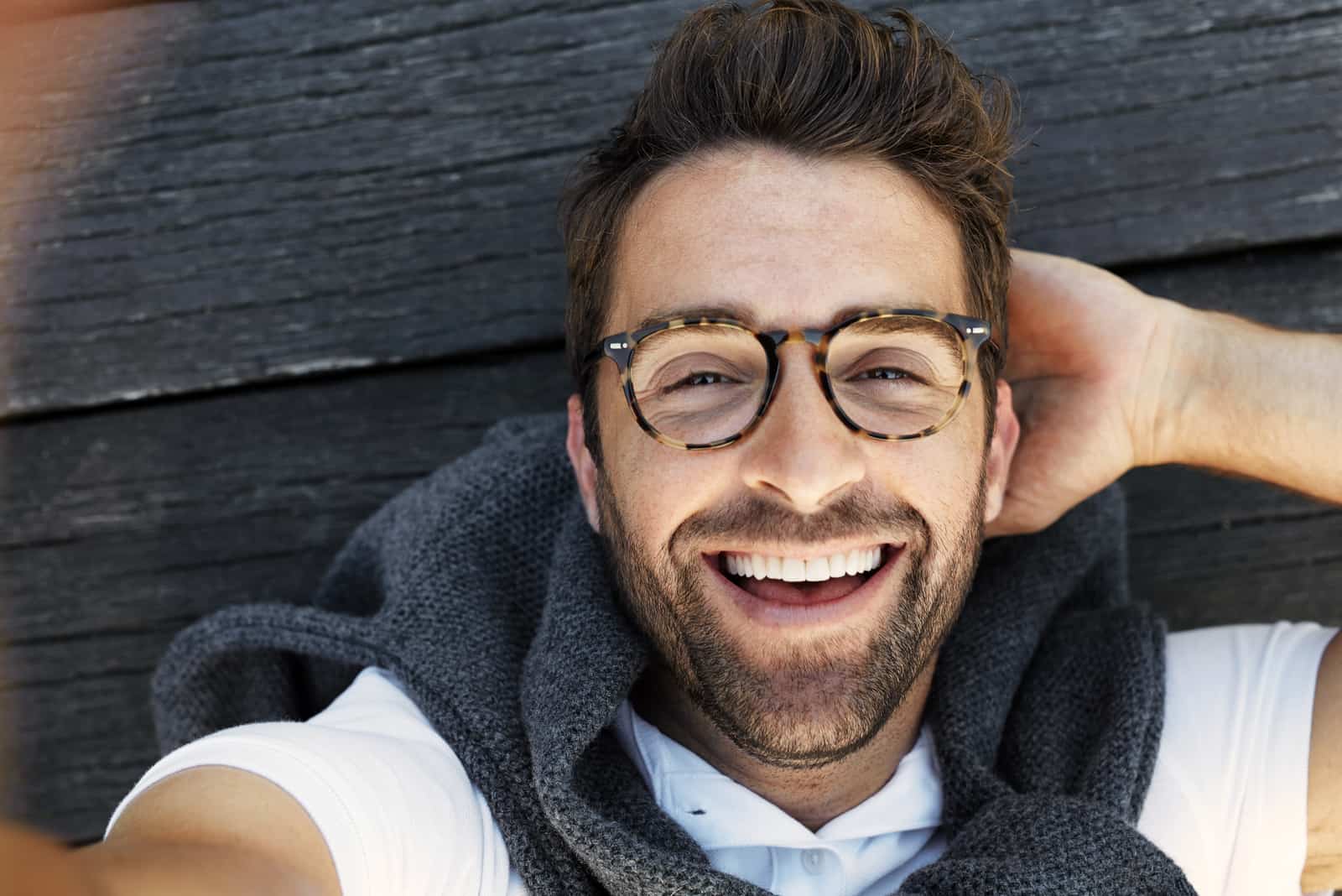 un hombre sonriente se tumba en el muelle y se hace una foto