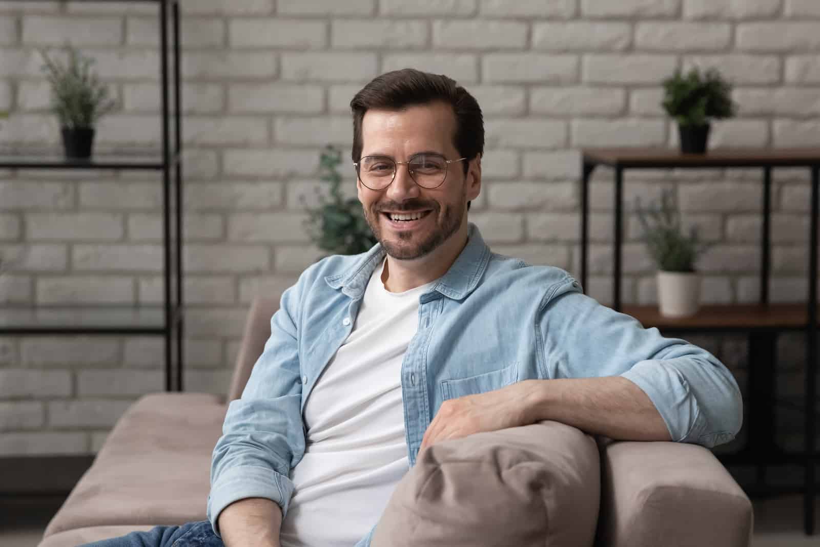 a smiling man sits on the couch