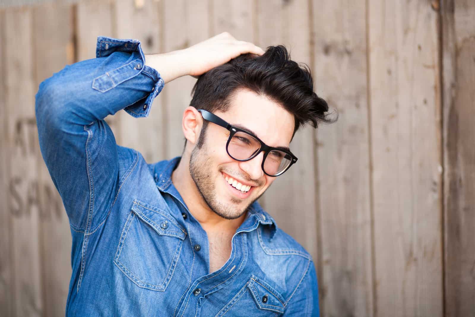 a smiling man touches his hair