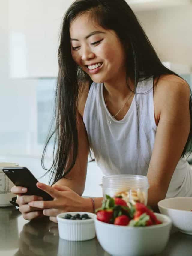 woman standing in kitchen texting