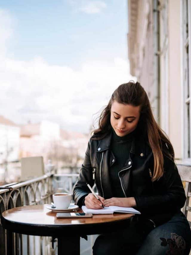 a beautiful woman sits at a table and writes