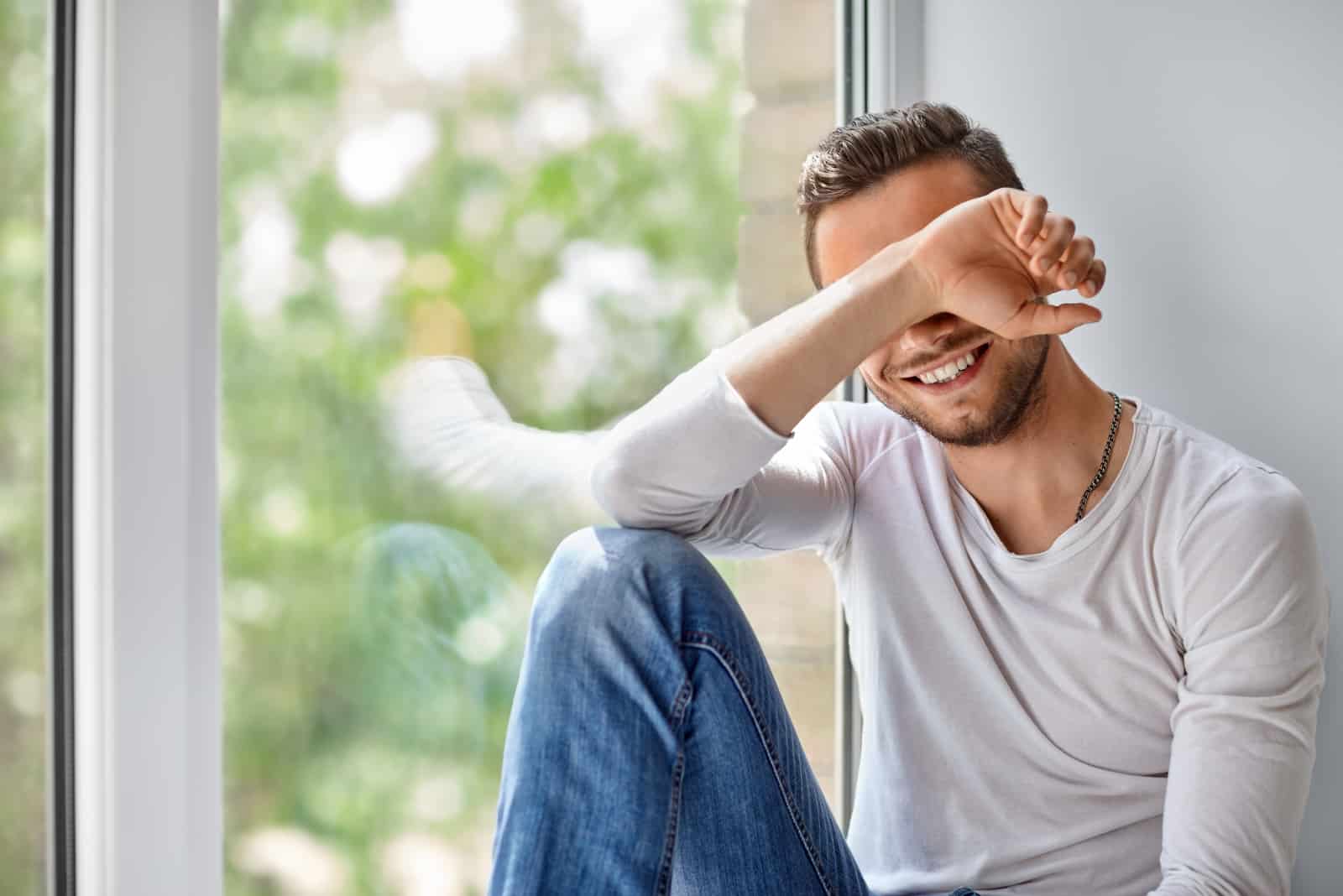 happy young man sitting by window