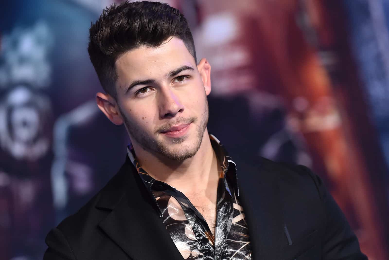 el hermoso Nick Jonas se para y mira delante de él