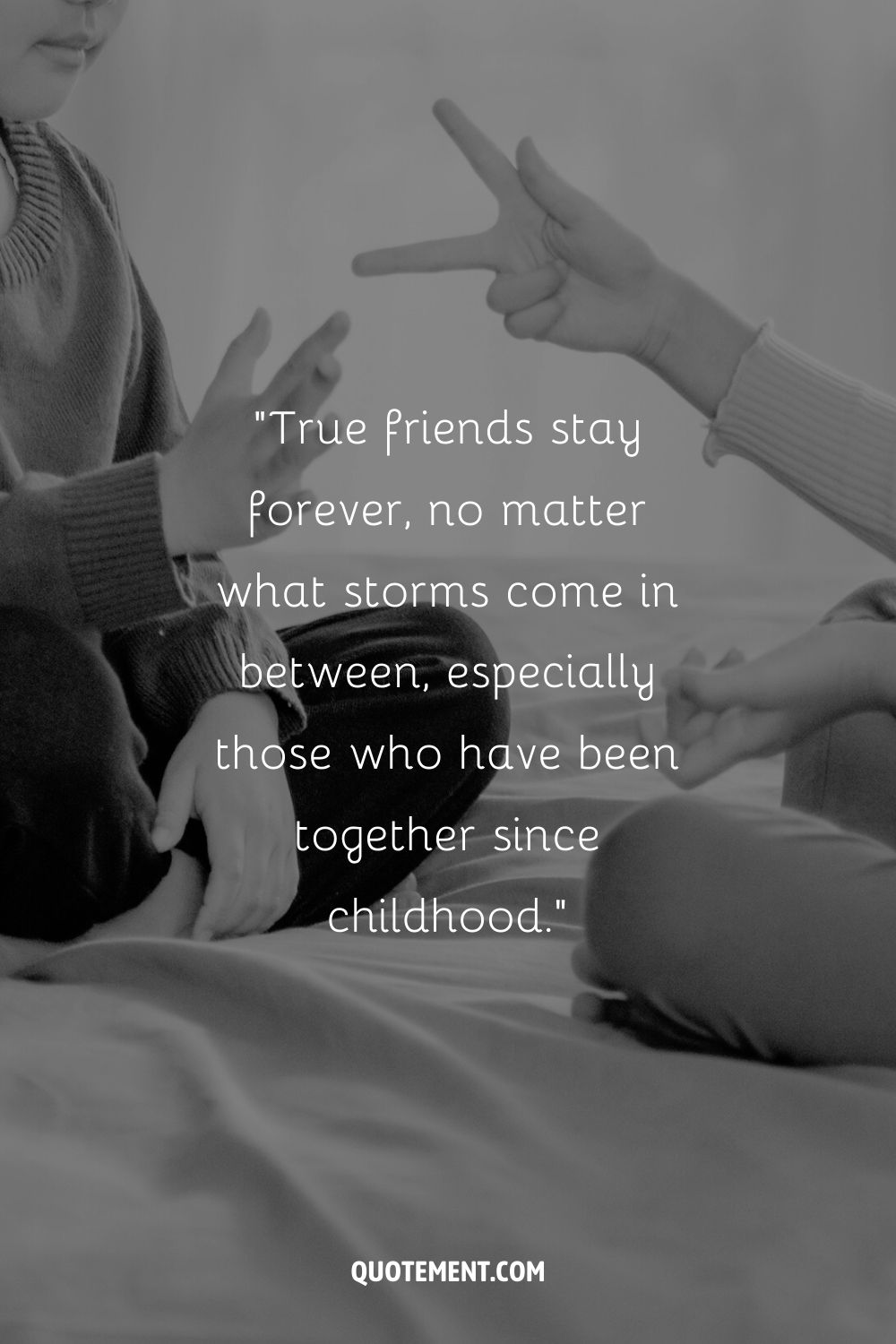 two kids enjoy a hand game on the bed representing friends forever quote
