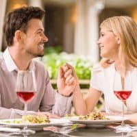 Young smiling couple enjoying the meal in gorgeous restaurant and drinking wine