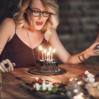 the woman holds her husband's hand while blowing into the cake