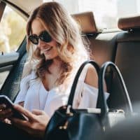 happy woman texting while sitting in car