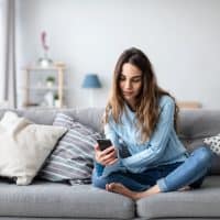 a woman sitting on the couch and a button on the phone