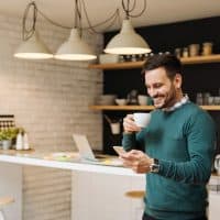 smiling man in kitchen holding his phone