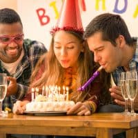 felices amigos en una fiesta de cumpleaños soplando velas en una tarta