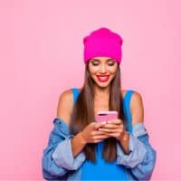 cute girl with pink hat holding phone and smiling