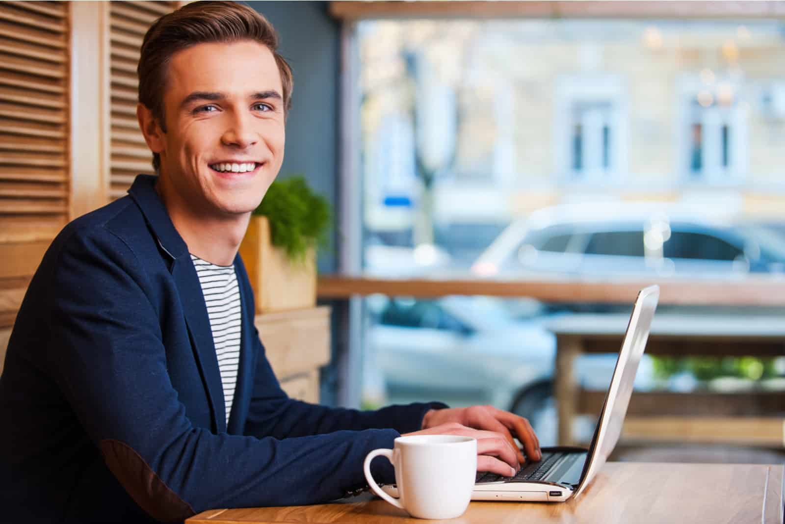 Handsome young man working on laptop and smiling