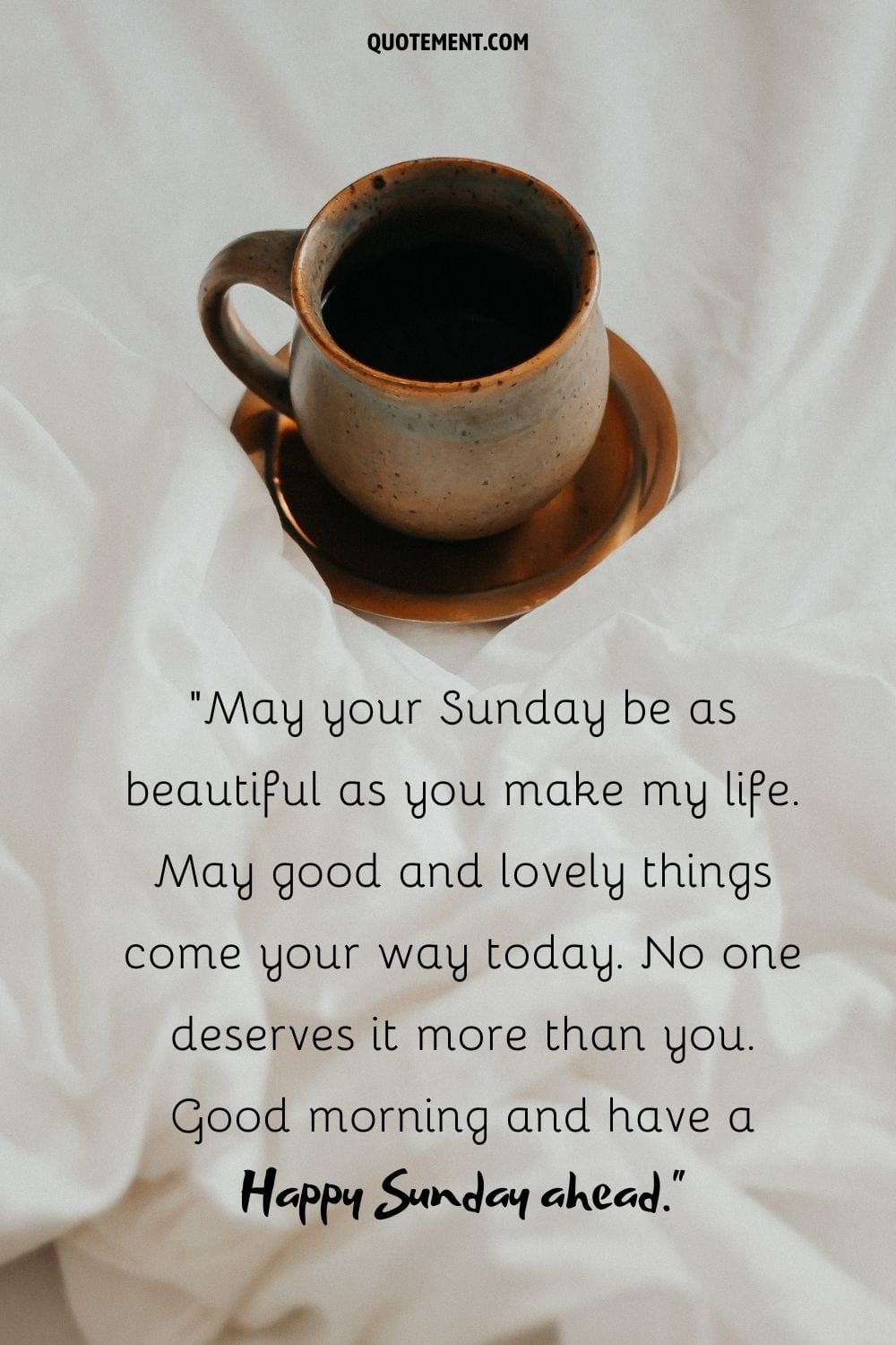 a brown coffee mug on the bed sheets representing good morning happy sunday quote