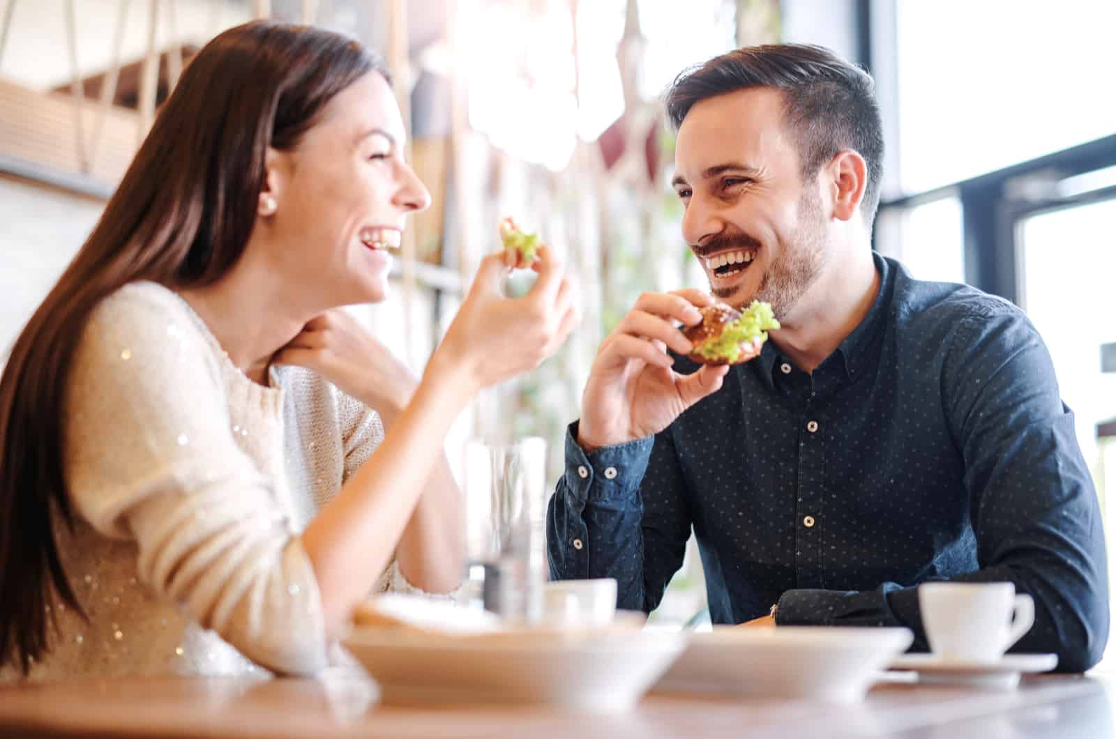 couple laughing while having a cup of coffee