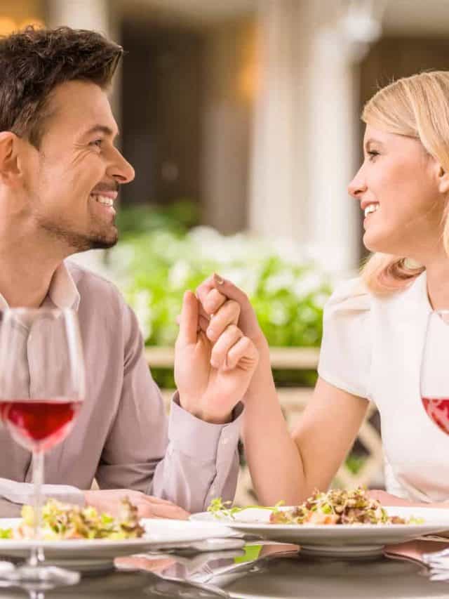 Young smiling couple enjoying the meal in gorgeous restaurant and drinking wine