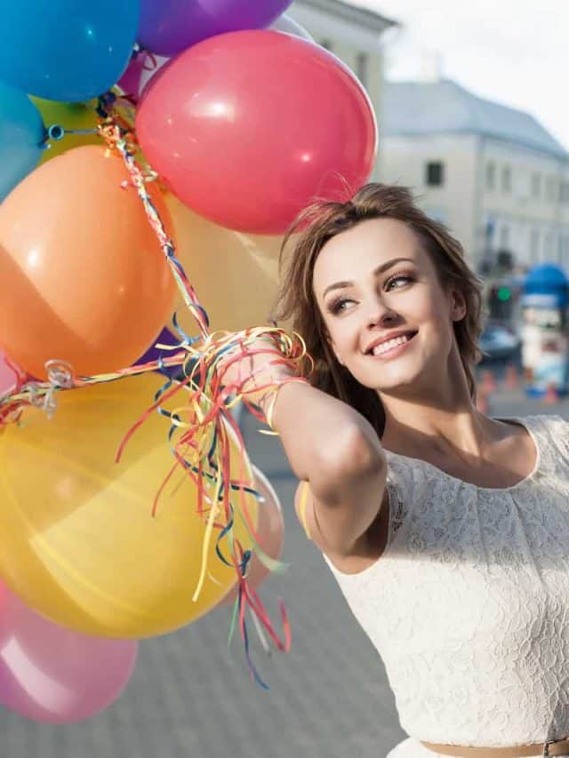 a smiling woman with balloons in her hand