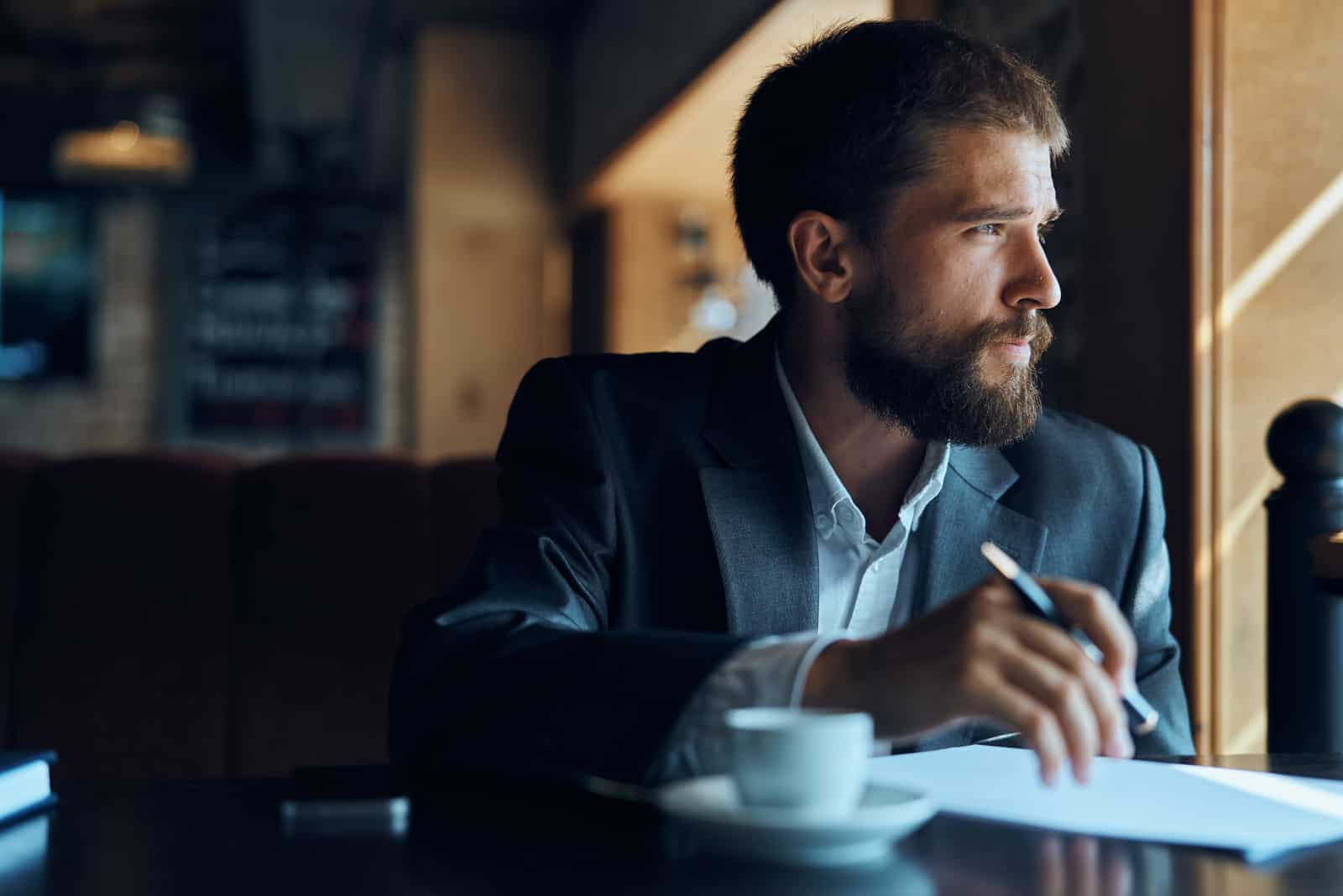 man sitting at table looking through window