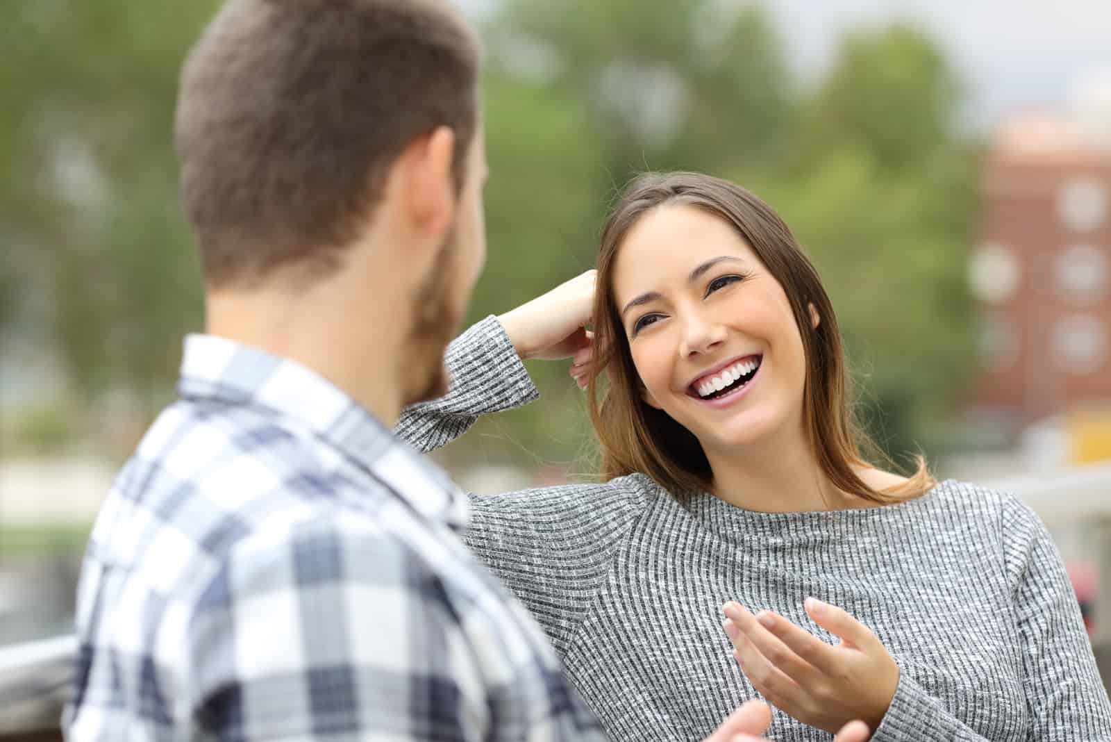 mujer sonriente hablando con hombre al aire libre