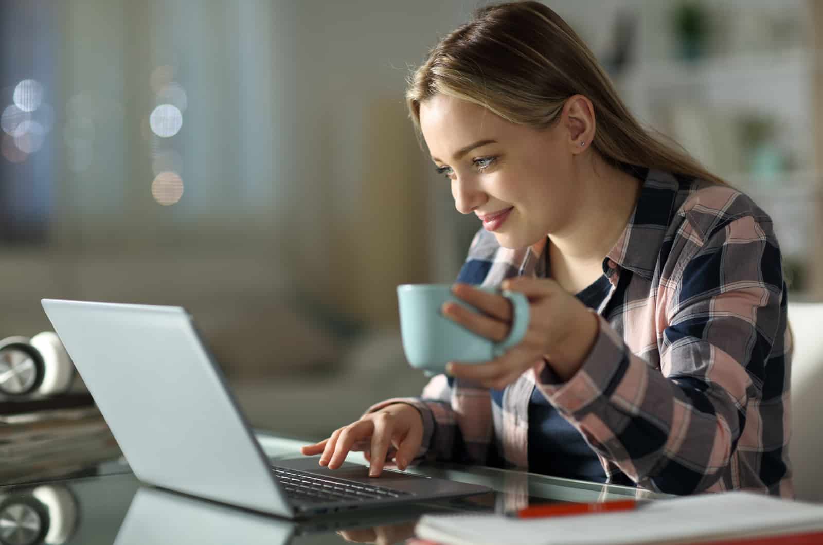 woman on laptop and holding a cup of tea