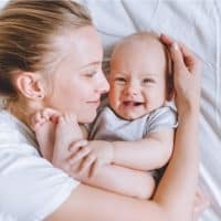 young mother enjoying with her baby on the bed