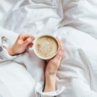 mujer con una taza de café en la cama