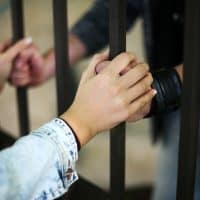 couple holding hands while boyfriend is behind bars