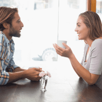 hombre y mujer sonrientes sentados a la mesa y hablando