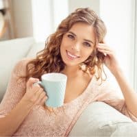 mujer sonriente con pelo largo castaño bebiendo té