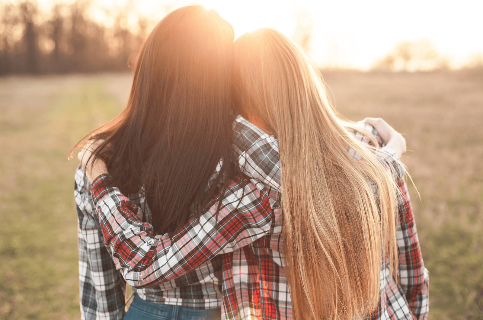 Dos jóvenes mirando la puesta de sol y abrazándose