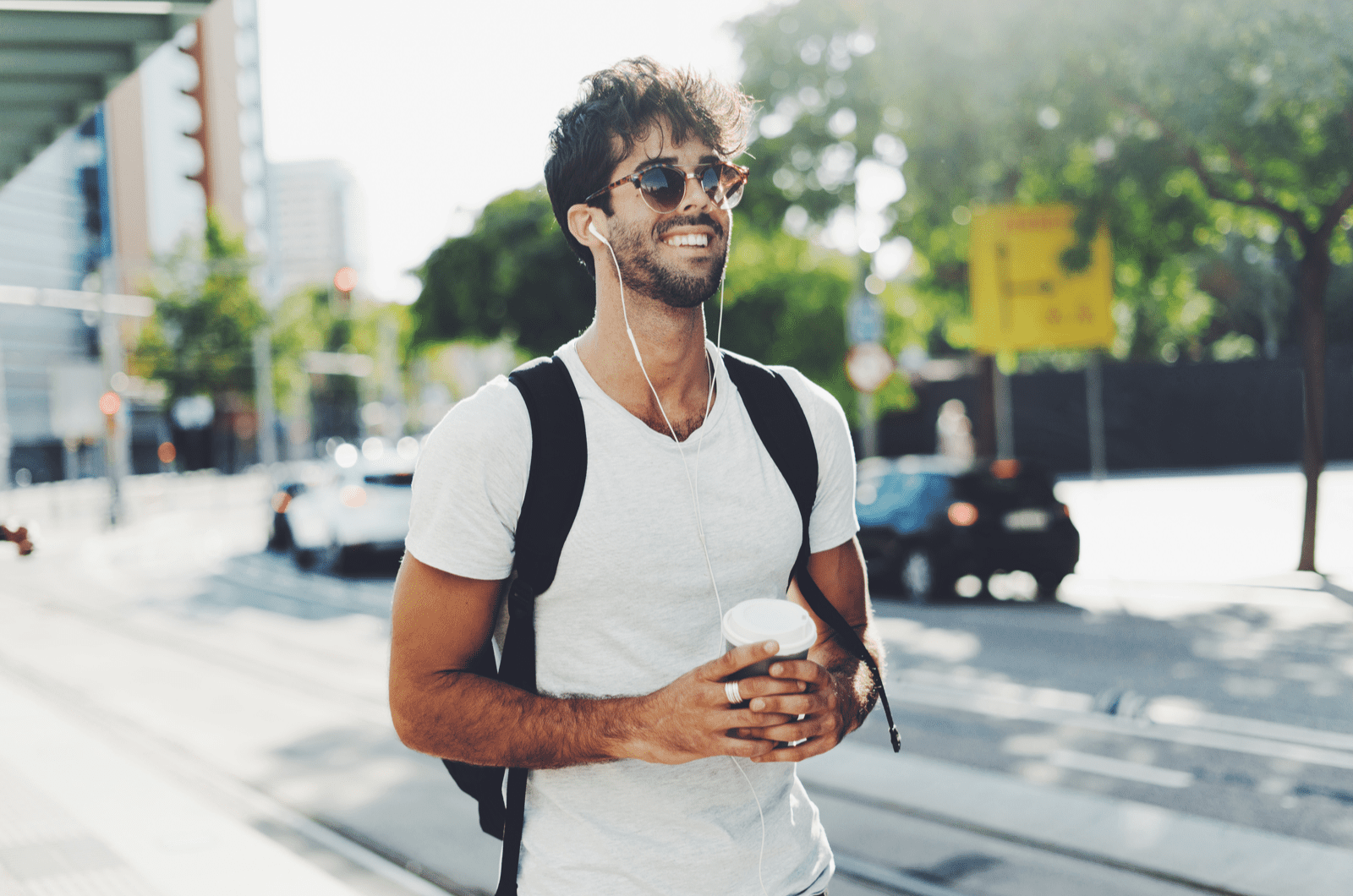 a smiling man with frizzy hair walks down the street