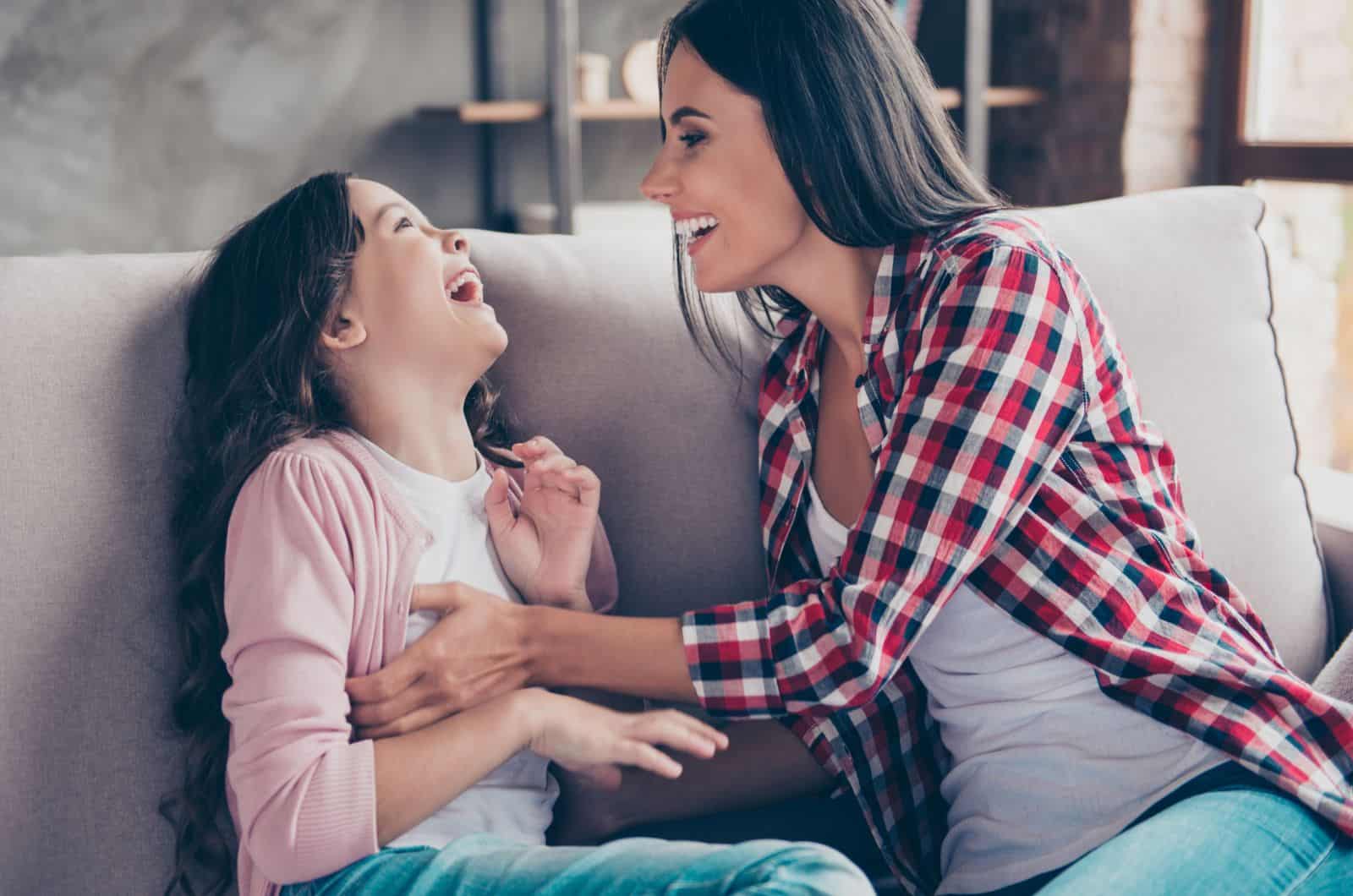 tía haciendo cosquillas a la niña en el sofá