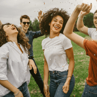 smiling friends are dancing in the meadow