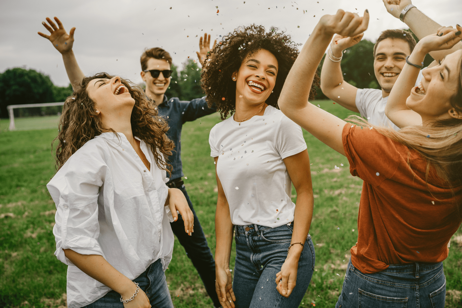 smiling friends are dancing in the meadow