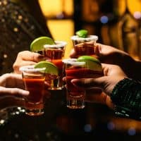 friends with raised tequila glasses in a bar