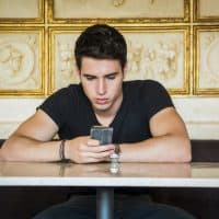 hombre sentado en un café enviando mensajes de texto