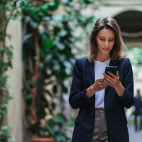 a beautiful woman is standing and holding a mobile phone in her hand