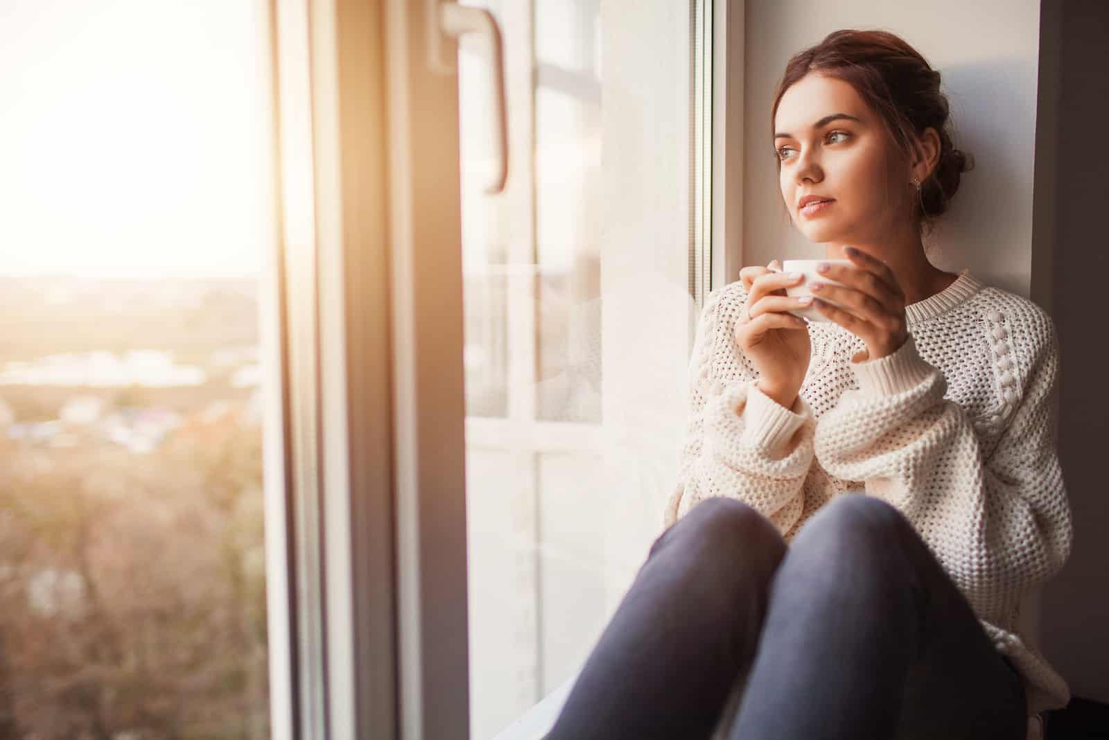 woman sitting by window drinking tea