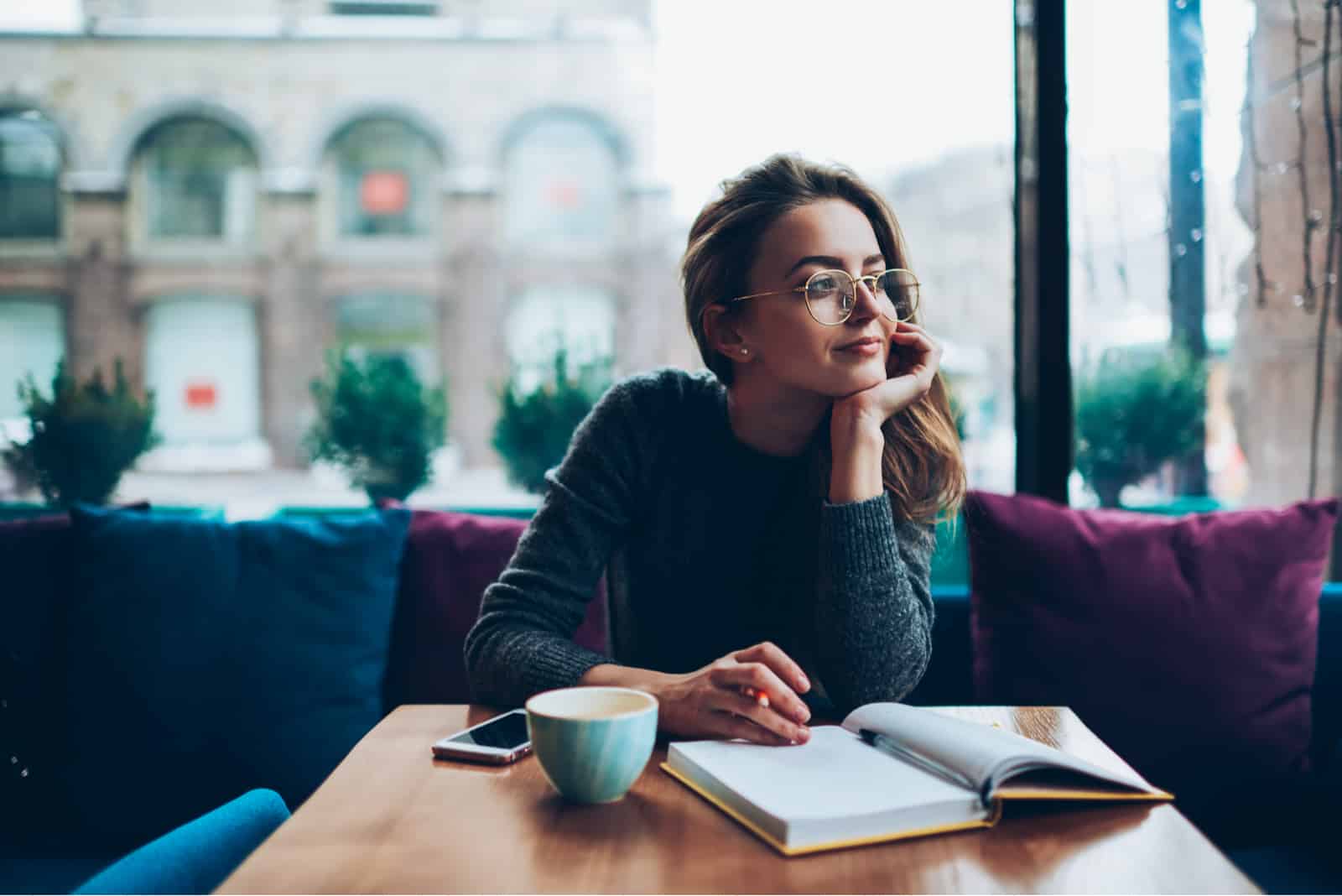 mujer sentada en un café escribiendo en un cuaderno