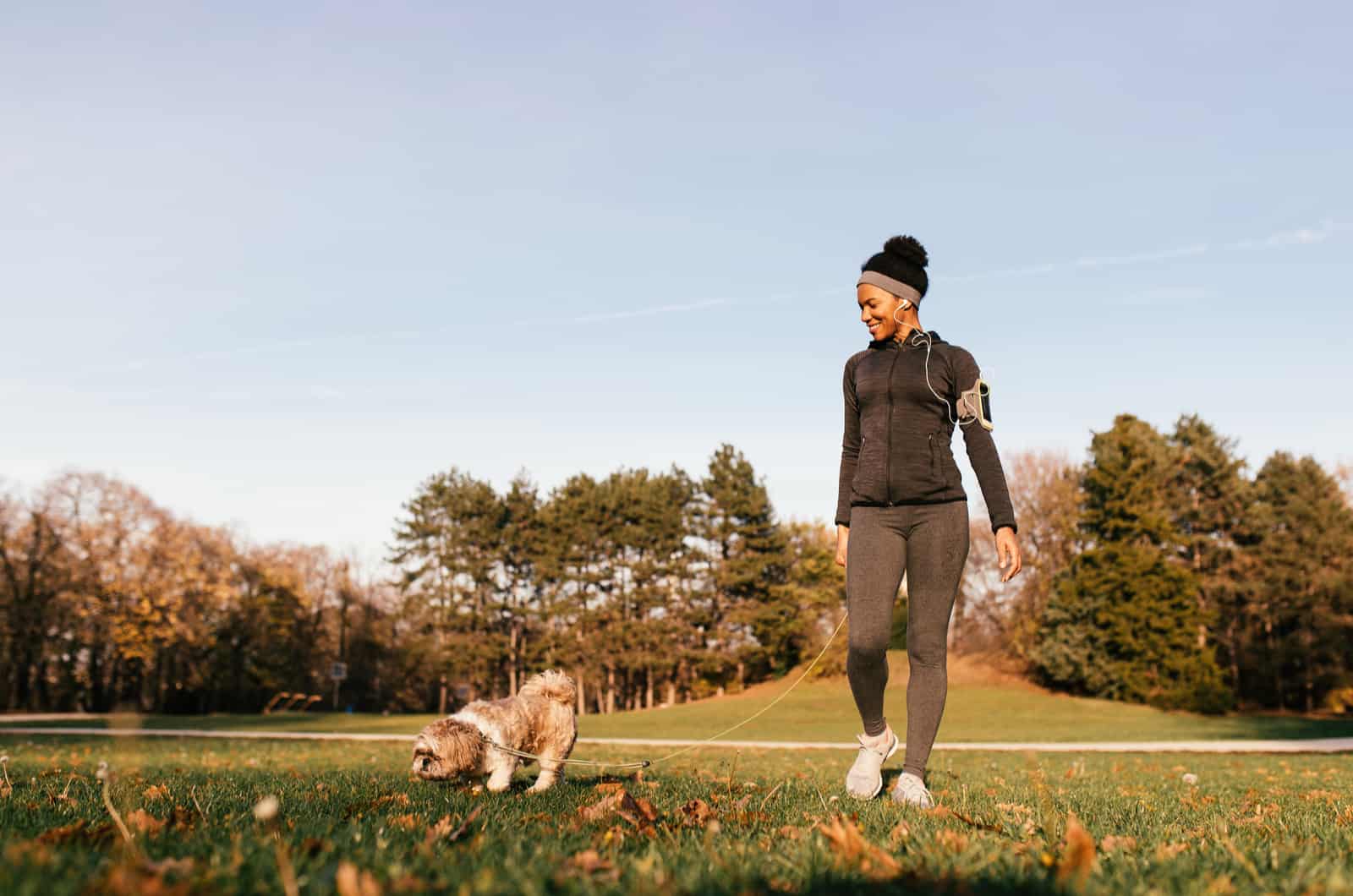 mujer joven paseando al perro al aire libre