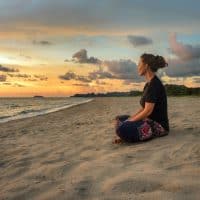 mujer sentada sola en la playa al atardecer