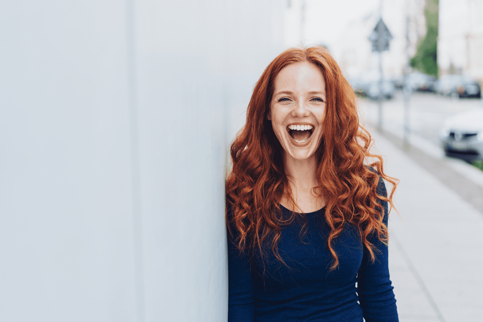 una mujer sonriente apoyada en la pared