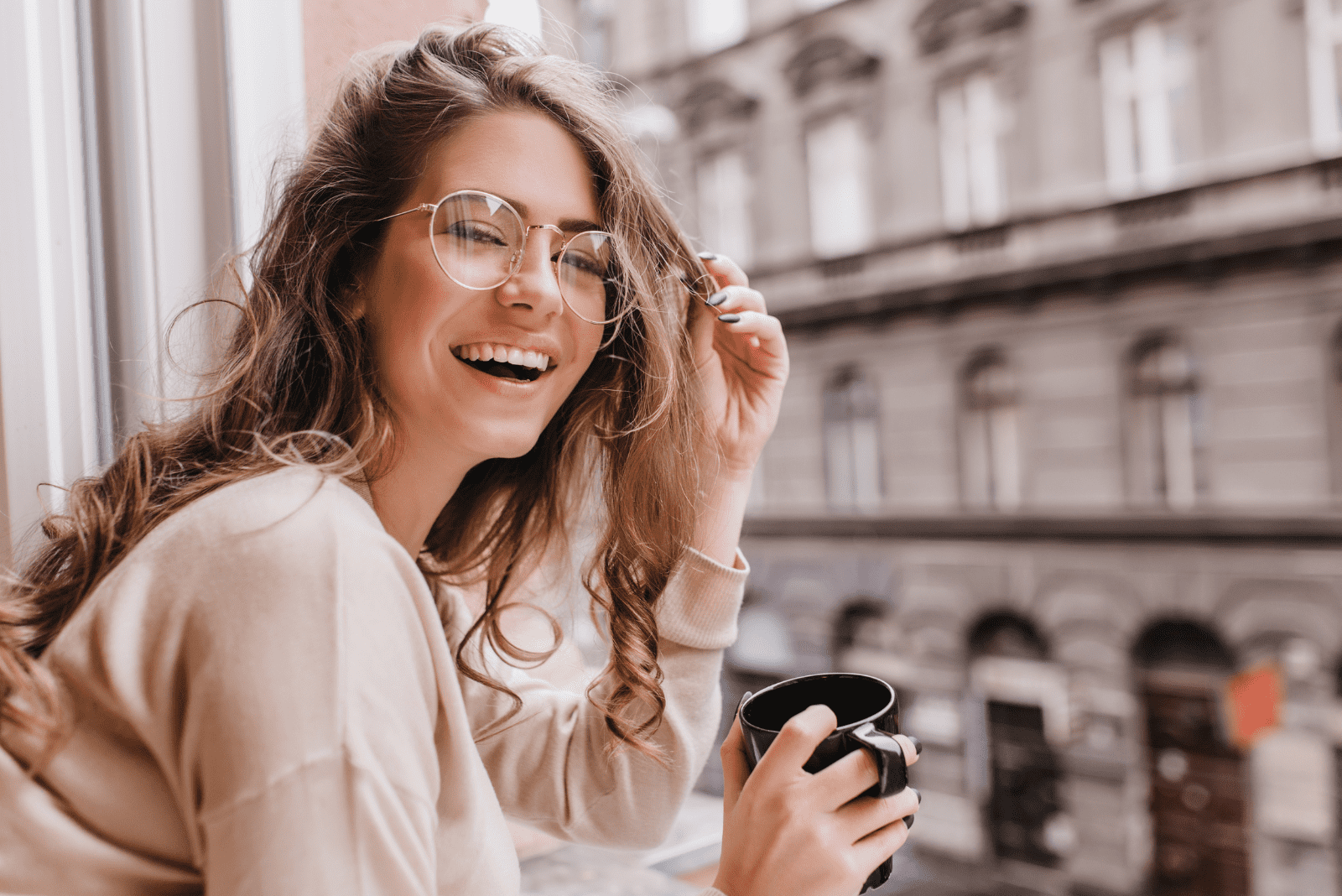 hermosa mujer sonriente de pie en el balcón y bebiendo café