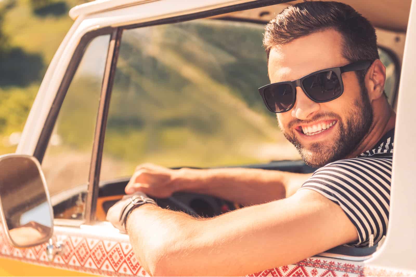 hombre guapo y sonriente sentado en su monovolumen